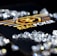 A collection of sparkling, clear gemstones surrounds a dark surface featuring the prominent logo and text 'Real Poker.' The logo design includes gold and white elements set against a black background.